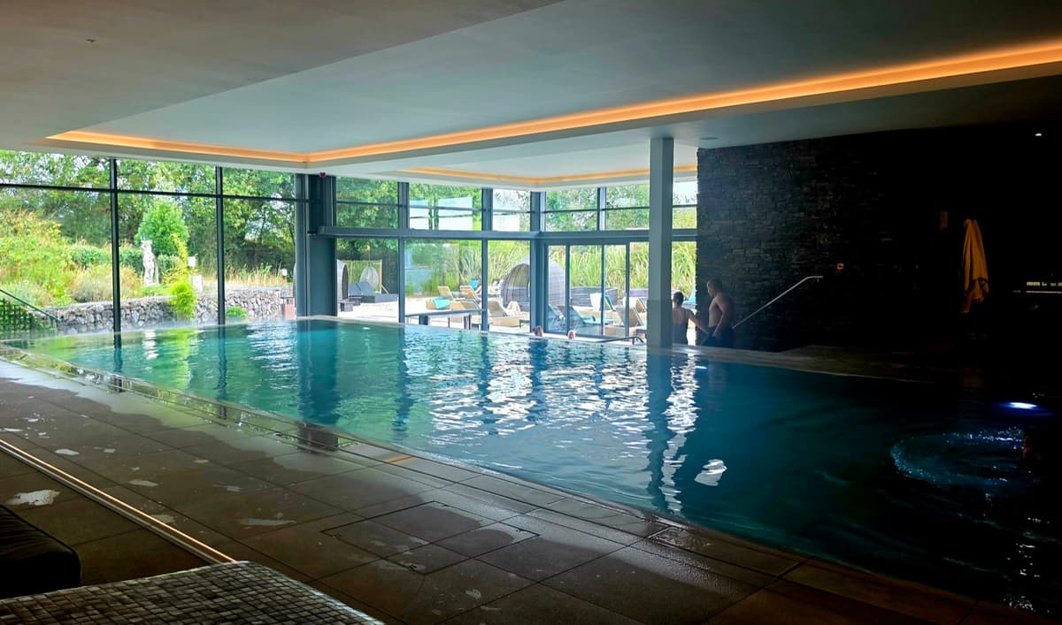 The indoor pool at Gaia Spa, Boringdon Hall, with floor-to-ceiling glass looking out to the gardens and a stone feature wall